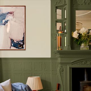 A living room with a mantel painted green and decorated with tall candles