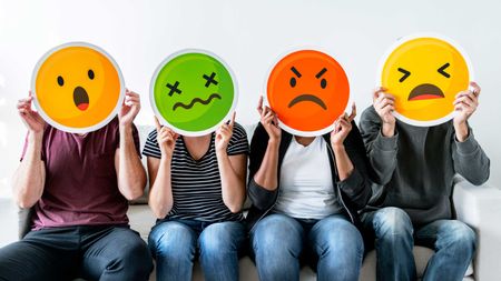 Four people holding up frustrated emoji faces