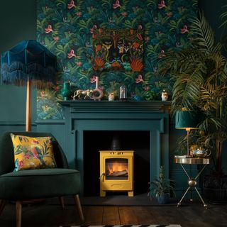 Dark green living room with bold wallpaper on the chimney breast and the fire surround painted to match