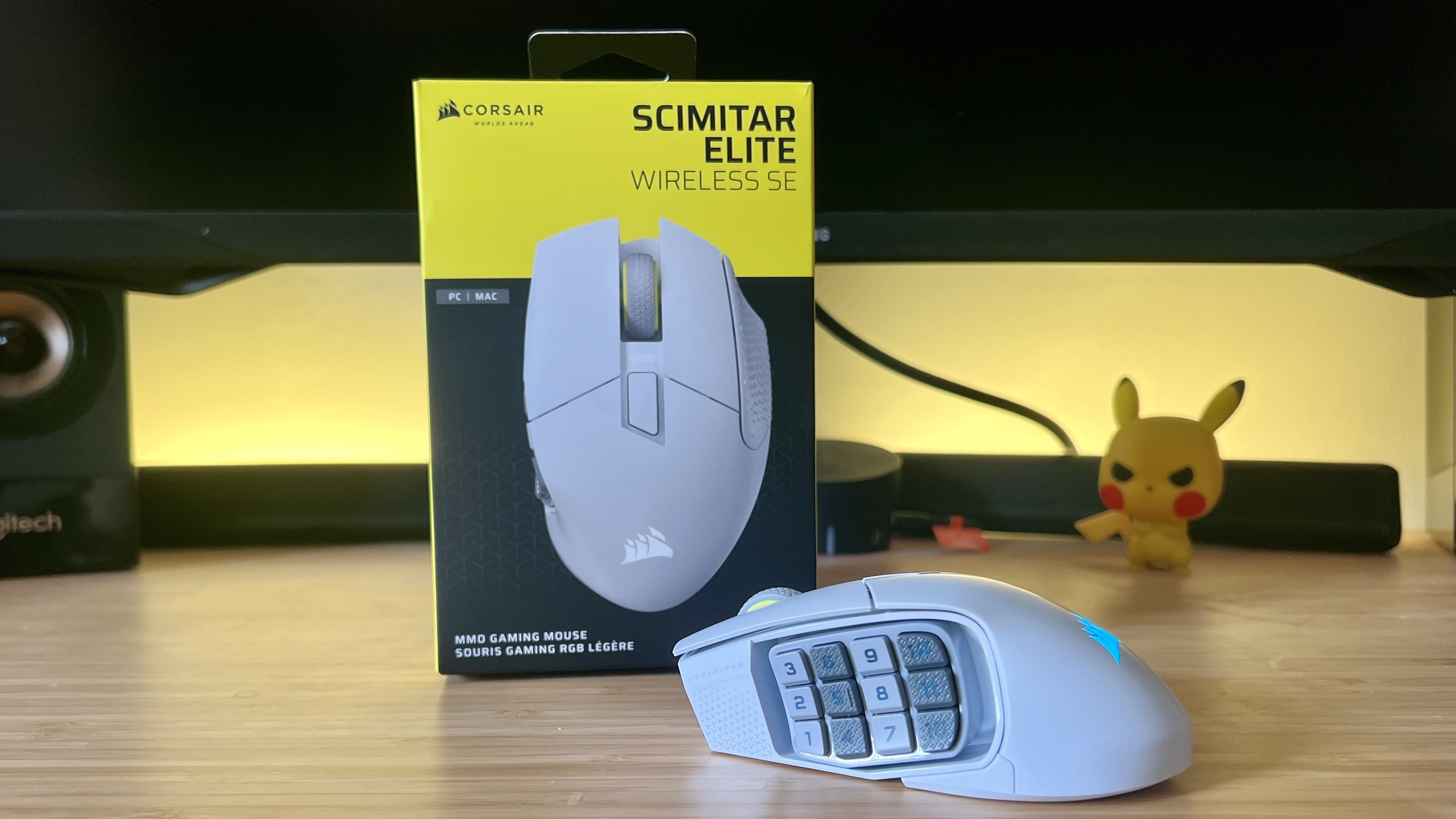 Corsair Scimitar Elite Wireless SE gaming mouse with packaging on a wooden desk with yellow backlighting