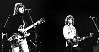 A black-and-white archive photo from 1975 captures Justin Hayward and John Lodge live onstage as they tour with Blue Jays, on a break from Moody Blues.