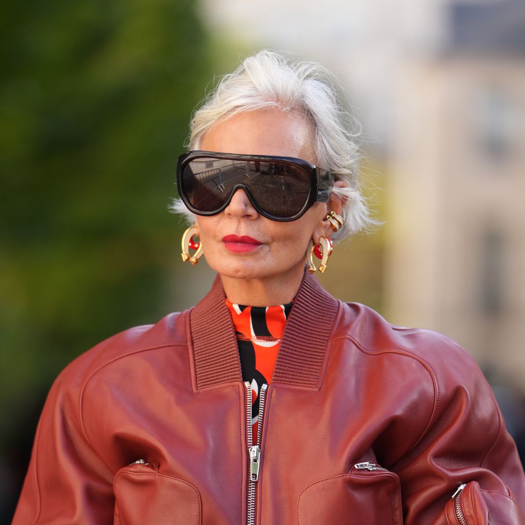 blush for mature skin Grece Ghanem wears short platinum-blonde hair with a side part, oversized black futurist sunglasses, gold hoop earrings, a gold cuff bracelet, gold rings, a tan leather bucket Picotin bag from Hermes with drawstring and gold hardware, a burgundy leather bomber jacket with ribbed collar and front zipper, a red and black high-neck printed top, a grey wool midi skirt with a center-front panel, outside Hermes, during Paris Fashion Week - Womenswear Spring Summer 2026, on October 04, 2025 in Paris, France