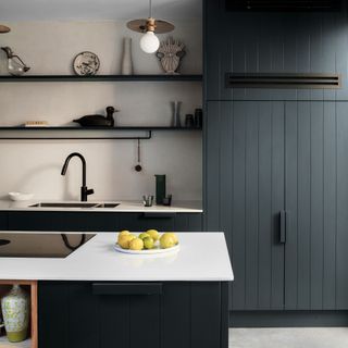 Kitchen with navy blue panelled kitchen cabinets, white worktop, and open shelving