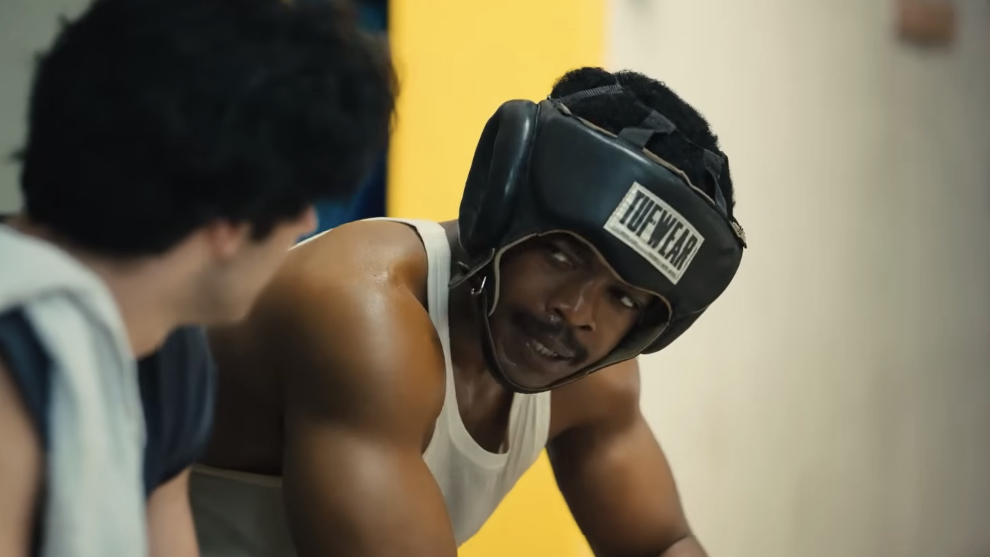 Stephan James' Carl Weathers in boxing helmet and undershirt talking to Anthony Ippolito's Sylvester Stallone in I Play Rocky