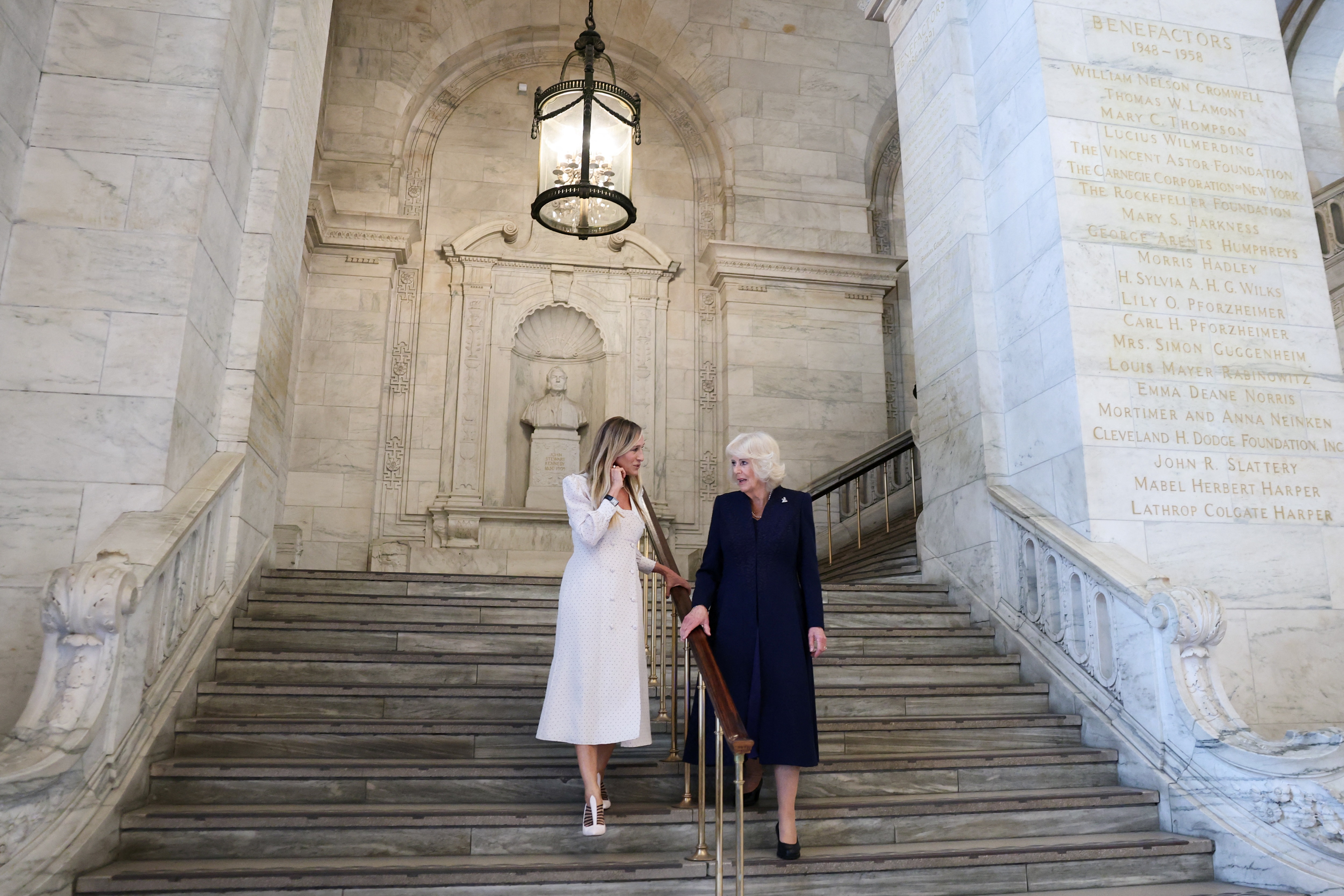 Queen Camilla and Sarah Jessica Parker walking down the stairs at the New York Public Library