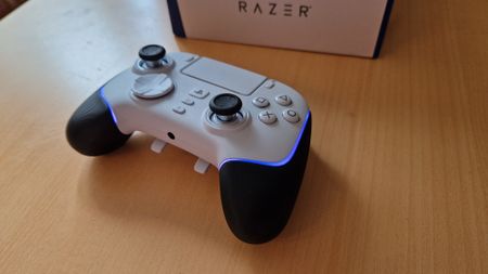 Razer Wolverine V2 Pro review image with the controller lying down on a table with the RGB light strips on blue
