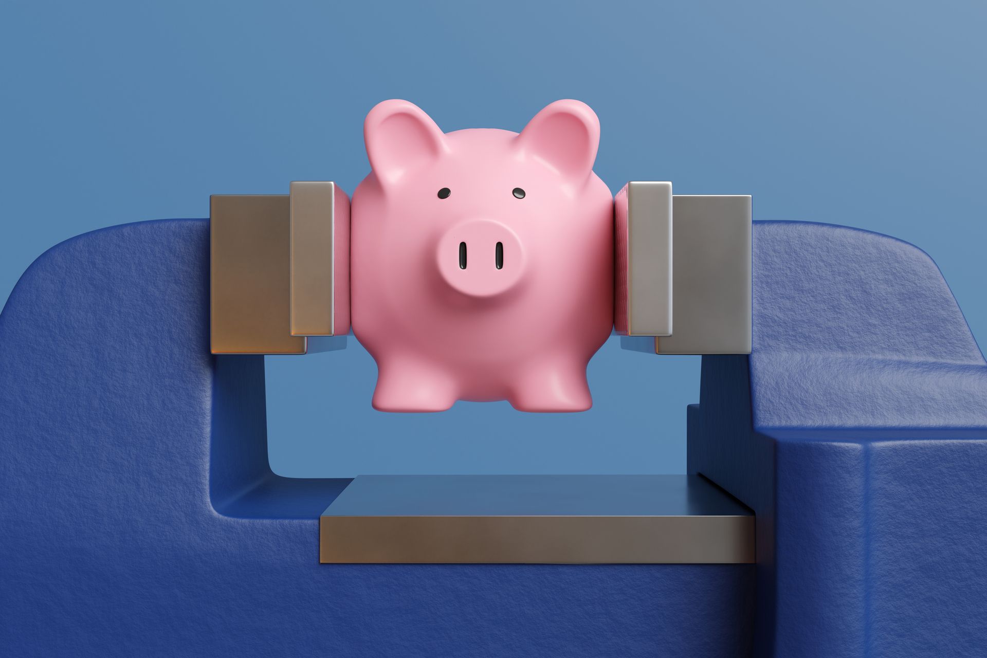 Pink piggy bank being pressed and crushed by a blue vice on blue background to illustrate the concept of financial stress