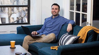 Stock trader David Nathanson sitting on a couch smiling at the camera.