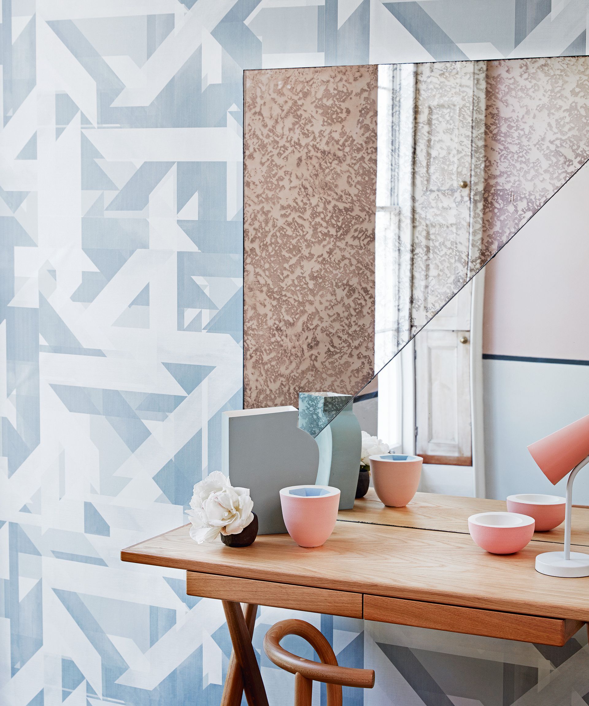 Side table with mirror above in front of patterned wallpaper