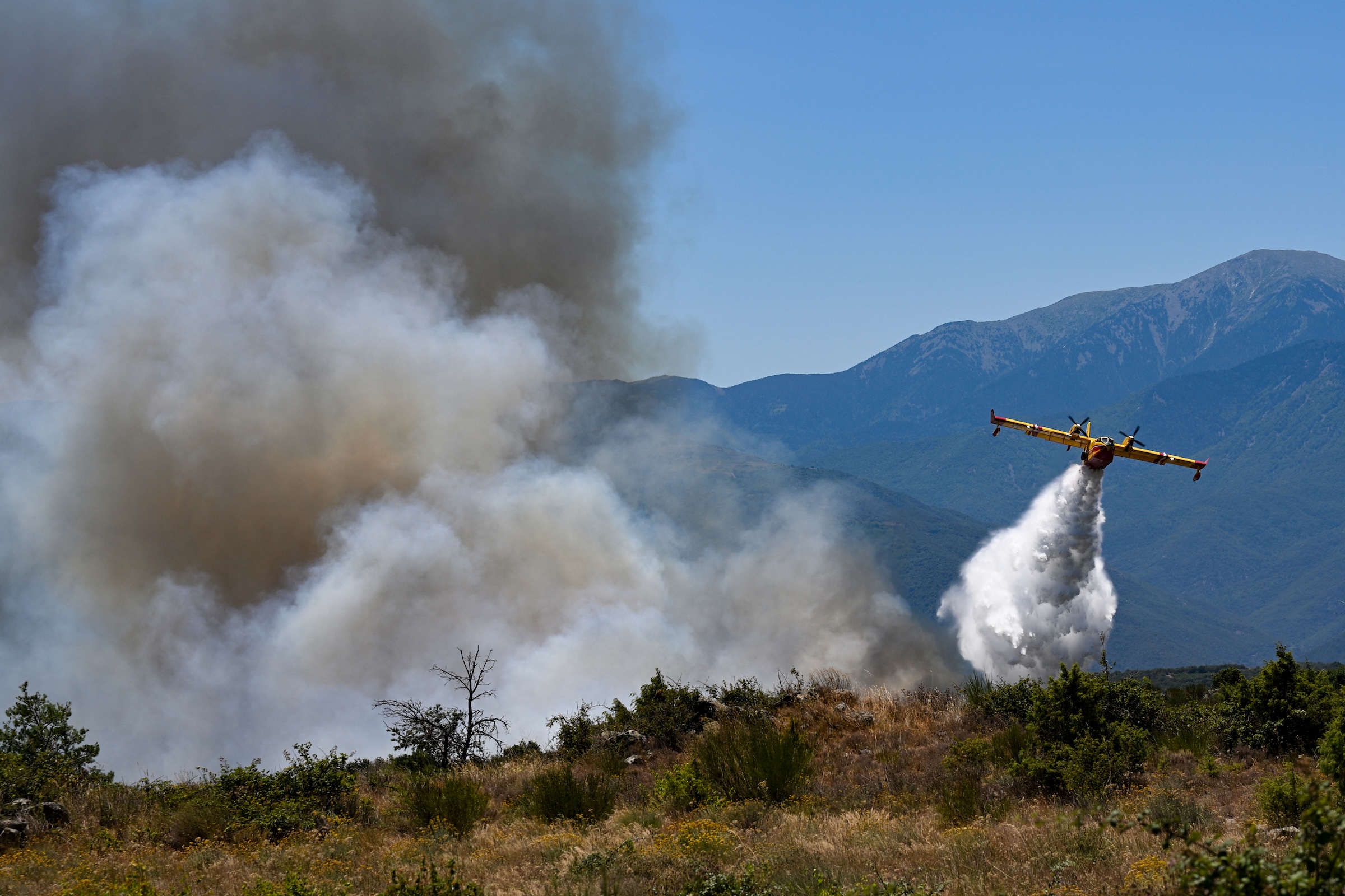 A Canadair CL-415 plane of France's Civil Security services drops water on a wildfire at the Col des Auzines, near Trevillach, southern France, on July 5, 2026. 