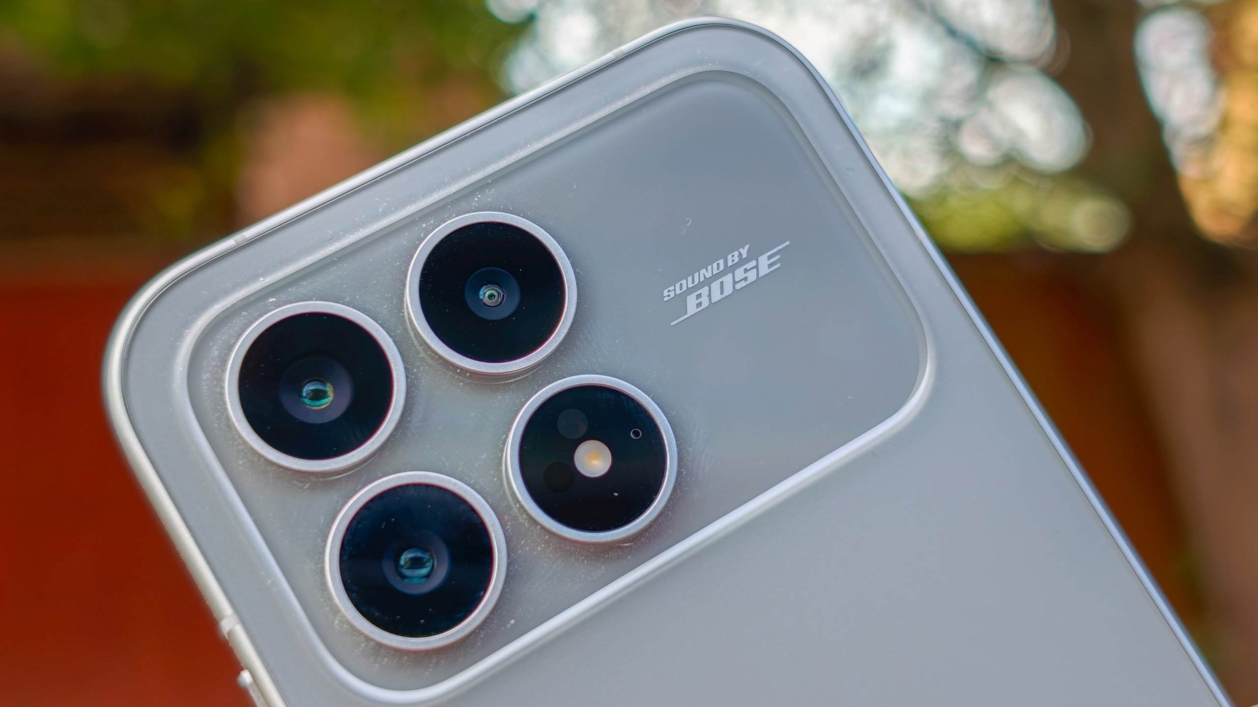 The Poco F8 Pro in Silver in the hand against a garden backdrop