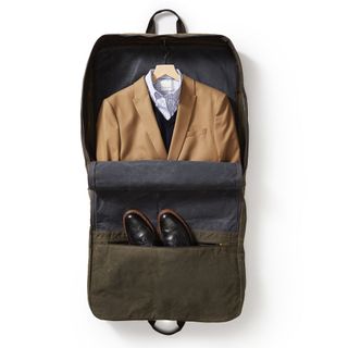 An open Mark & Graham Waxed Canvas garment bag showing a suit jacket and shirt and pair of shoes