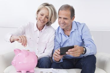 Mature Couple Calculating Coin In The Piggybank