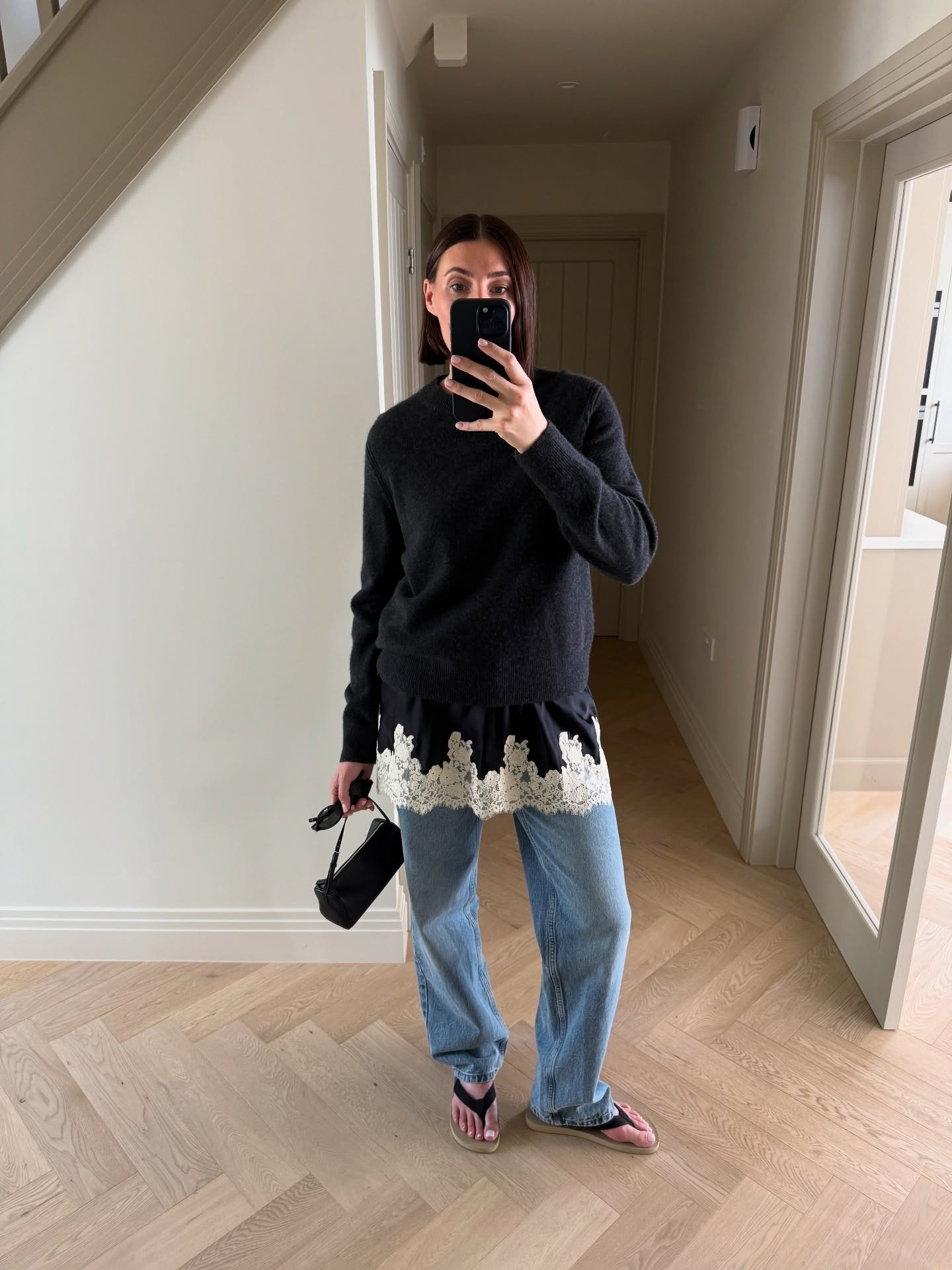 @sarahlouiseblythe wearing a sweater over a lace-trim slip dress with jeans and flip-flops.