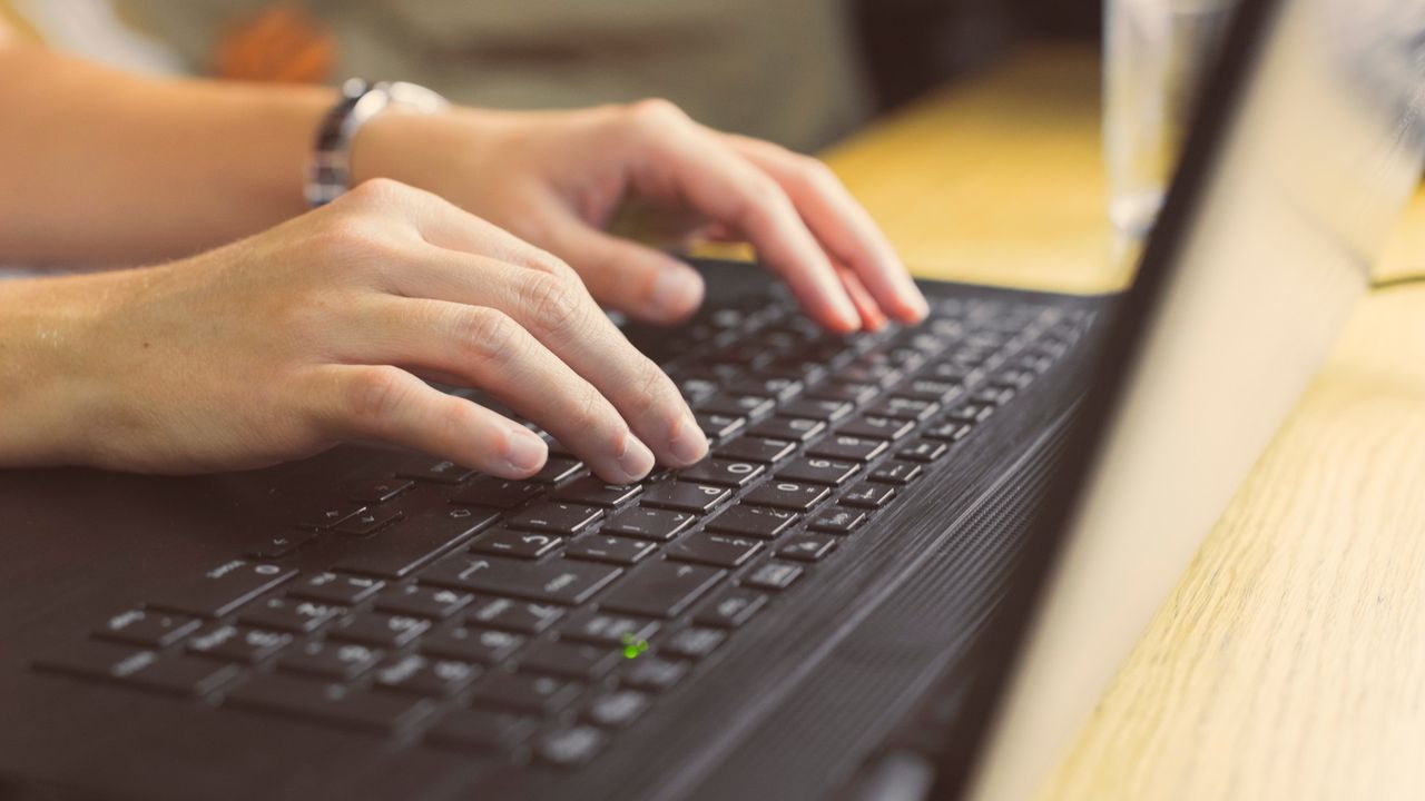 Hands typing on a laptop