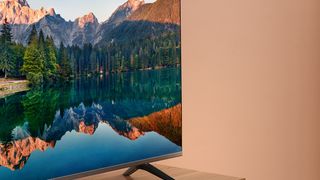 Amazon Fire TV 4 Series sitting on a wooden unit with a lake and forest on screen