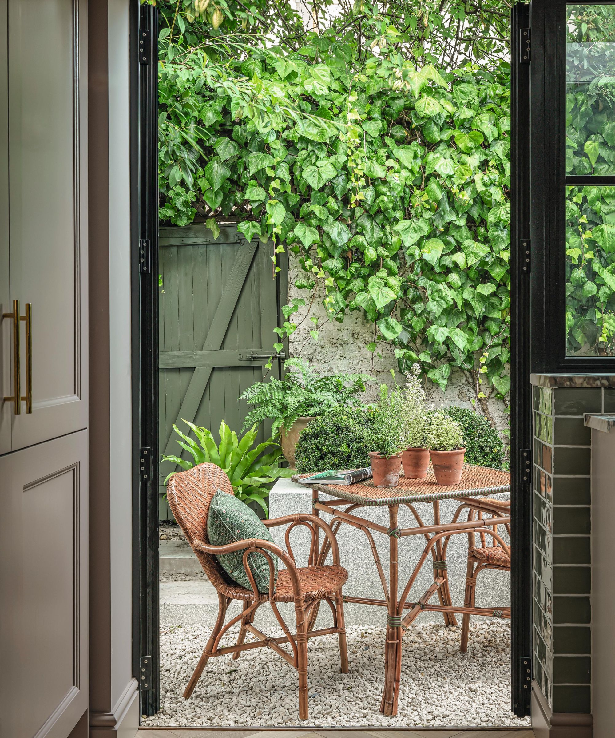 a london courtyard garden view through the window with an orange bistro table set