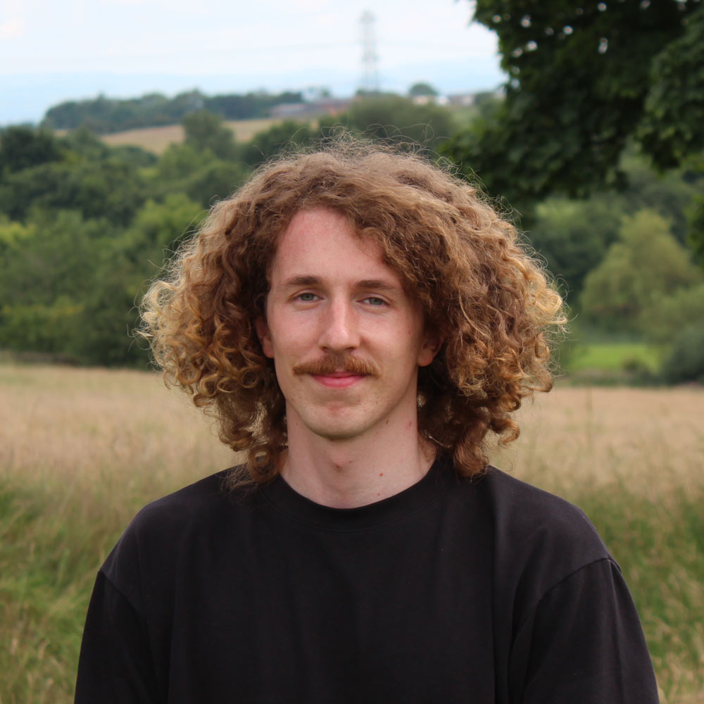 A portrait of Harry Bennett with a field and trees in the background.