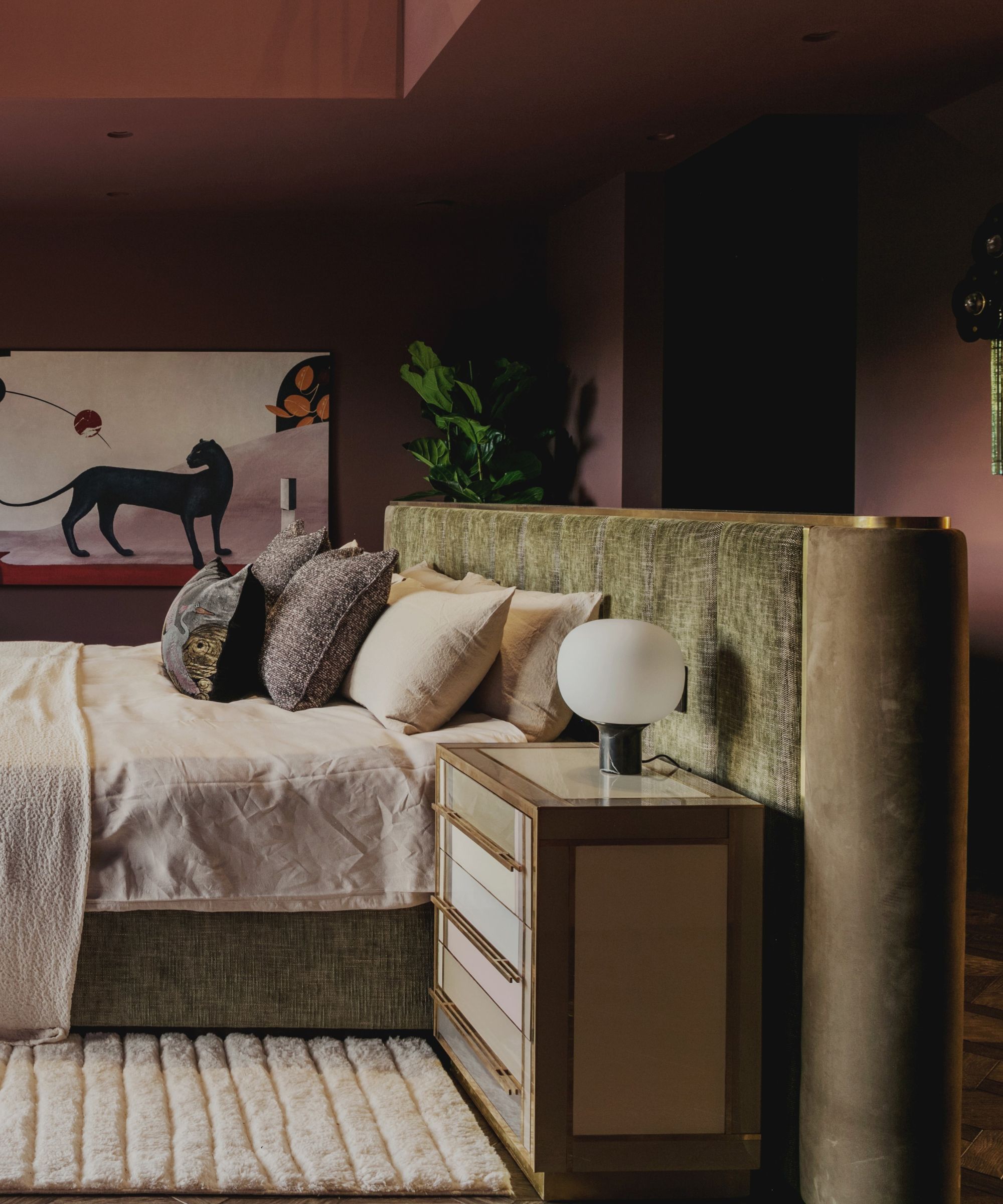 burgundy painted bedroom with green velvet upholstered headboard and a large panther wall painting