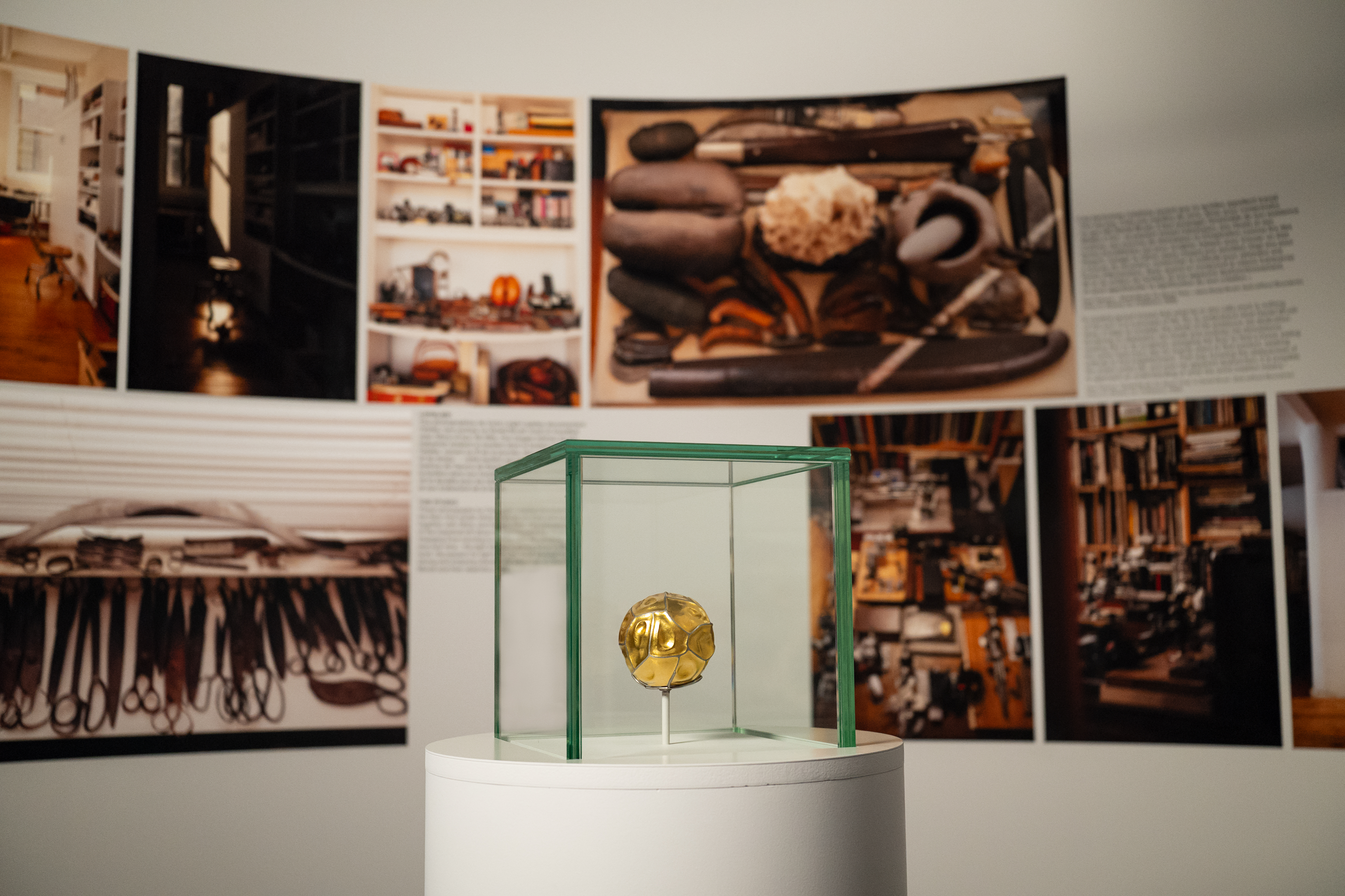 A gallery exhibit consisting of a glass box with a gold ball inside