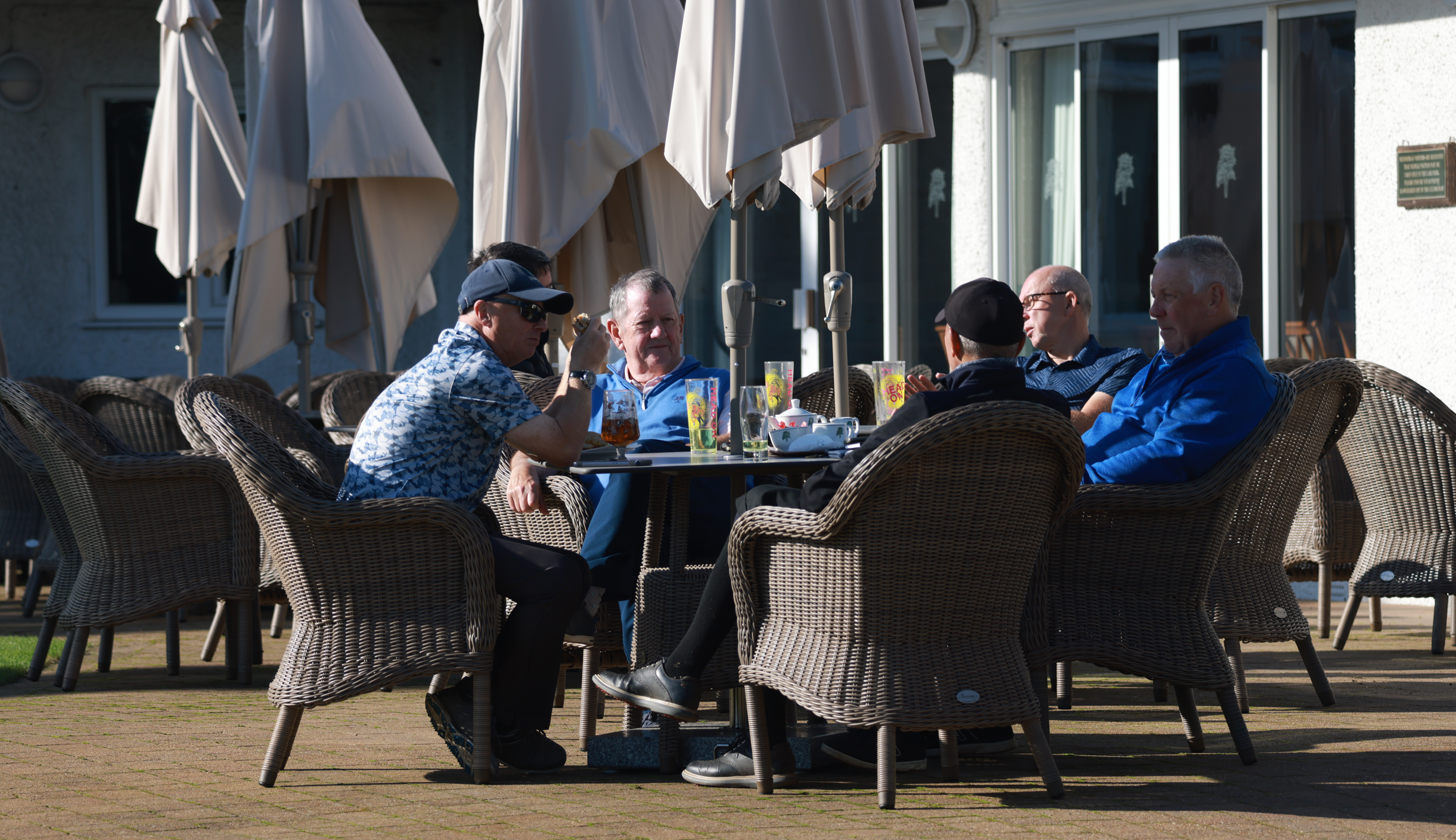 Golfers pose round a table with a beer