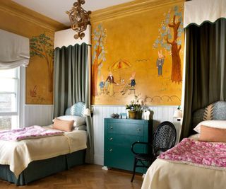 A childs bedroom with two single beds, a yellow painted wall mural covering the walls