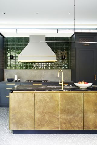 kitchen island with metallic finish with glossy green splashback