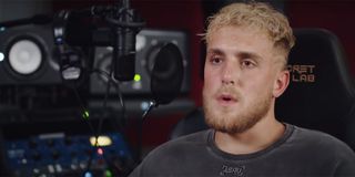 Jake Paul doing an interview in front of TV cameras with a black shirt on.