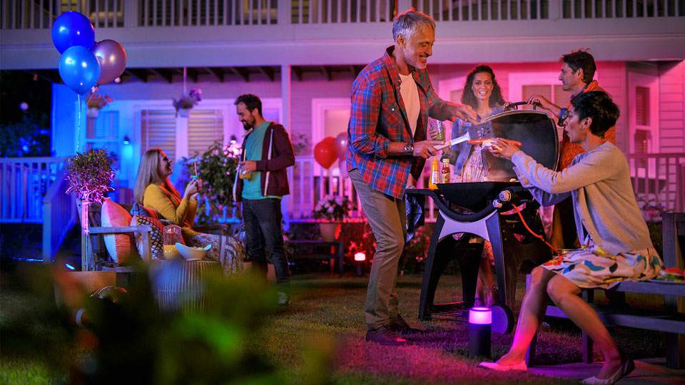 People at a barbecue lit by Philips Hue outdoor lights