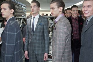 a room with male models in suits mostly looking at something to their right