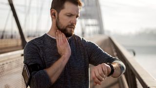 Man checking pulse on his neck and on GPS sports watch