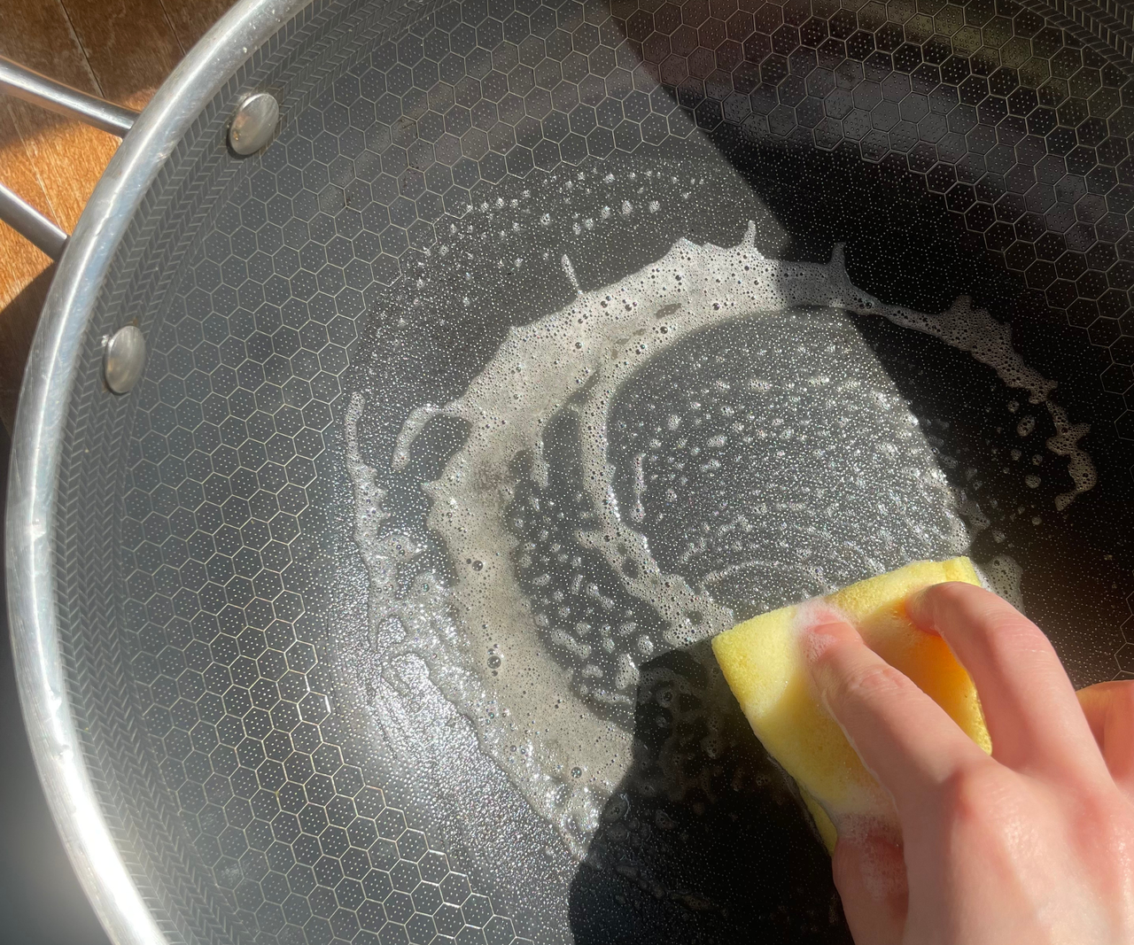 Using a yellow dish sponge to clean a HexClad wok