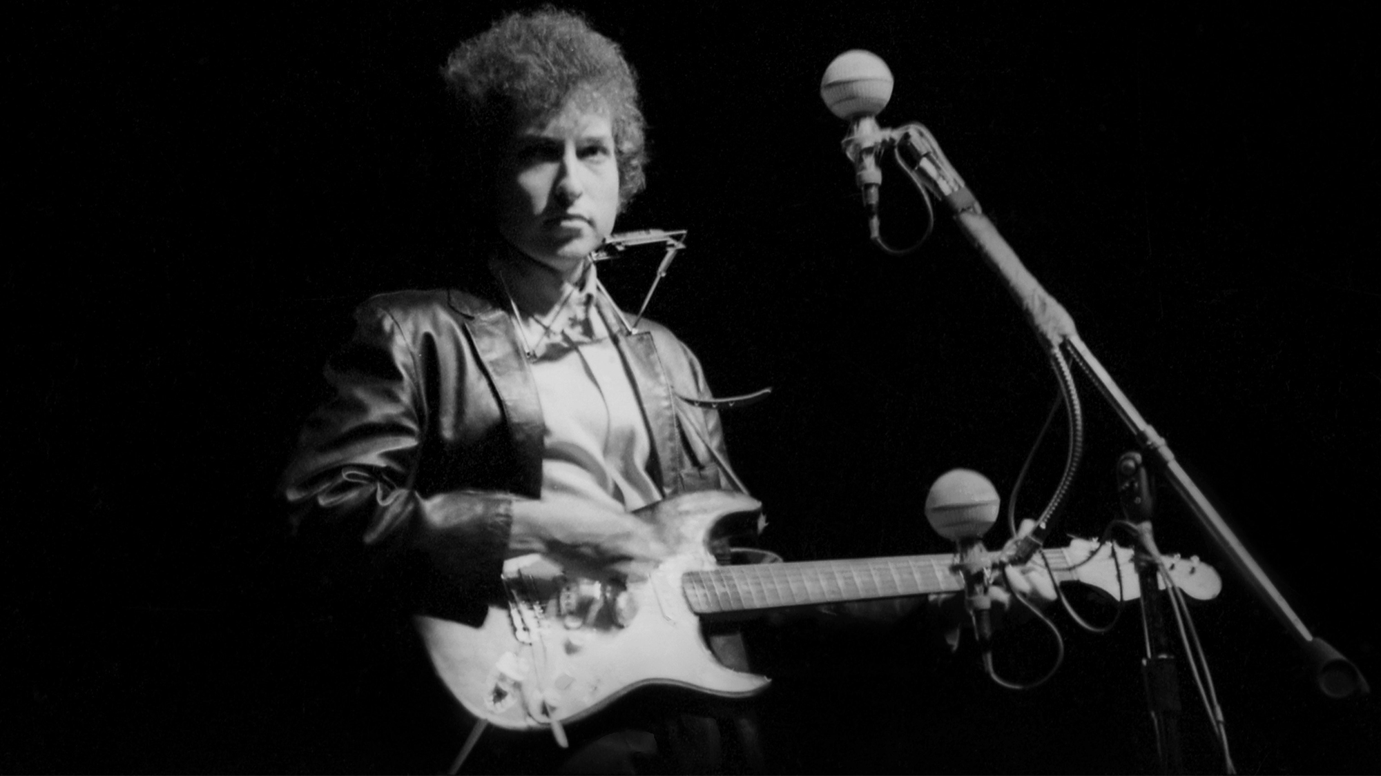 Bob Dylan plays a Fender Stratocaster electric guitar for the first time on stage as he performs at the Newport Folk Festival with guitarist Mike Bloomfield on July 25, 1965 in Newport, Rhode Island.