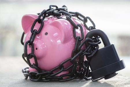 Piggy bank secured with padlock chained up and locked