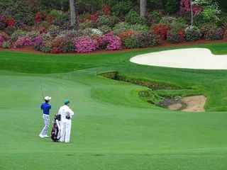 Kevin Na practices his wedges into the 13th green.