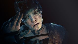 Hellblade's Senua reaching out towards the camera in a darken room