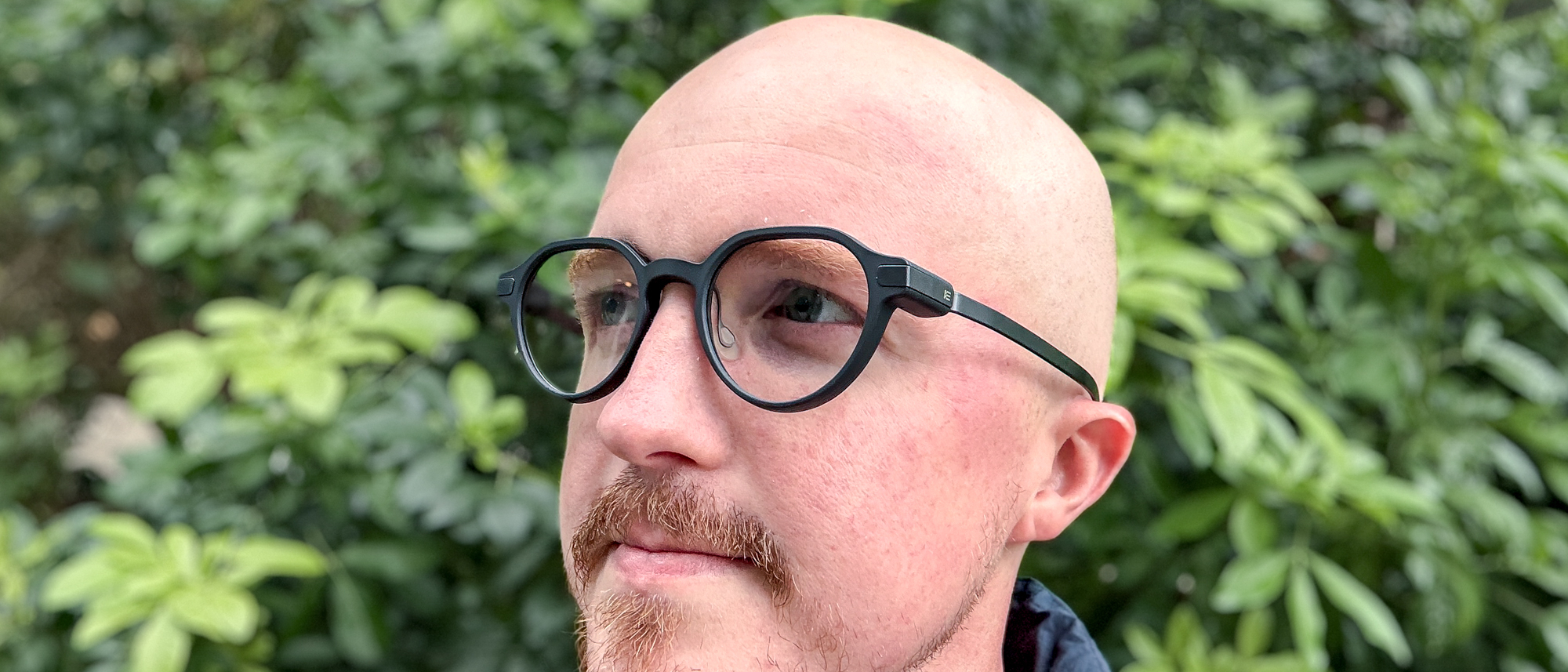 Even Realities G2 smart glasses on person with green bushes in background