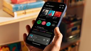 Den nya Sonos-appens startskärm visas på en iPhone som hålls upp av en person.