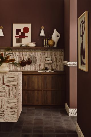 a dark brown kitchen with striped tiles and interesting artwork on the walls