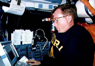 STS-41 Commander Richard N. Richards, at pilots station, uses Detailed Test Objective (DTO) Space Station Cursor Control Device Evaluation MACINTOSH portable computer on the forward flight deck of Discovery, Orbiter Vehicle (OV) 103. Richards tests the ro