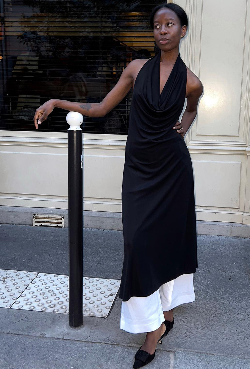 halter dress trend on a woman wearing a black midi dress layered over white linen pants and black pointed heels