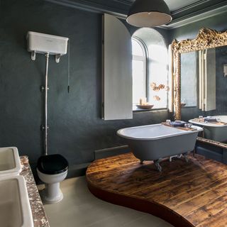bathroom with grey wall and bathtub and commode