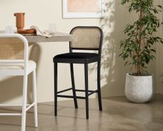 Made Raleigh Bar Stool in black, beside white version, with plant and wall art in shot