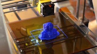 The square outline around the finished 3D printed astronaut print is how the ZMorph prepped and cleaned its print head. Note the removable brim under the astronaut, which helps the model stick to the print bed during the printing process.