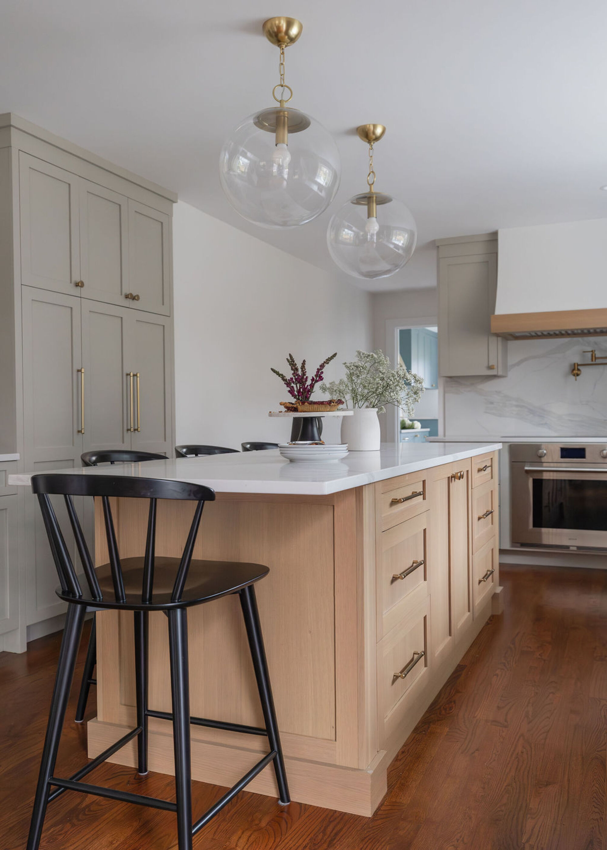 A kitchen with grey wall cabinetry and a wooden island in the center