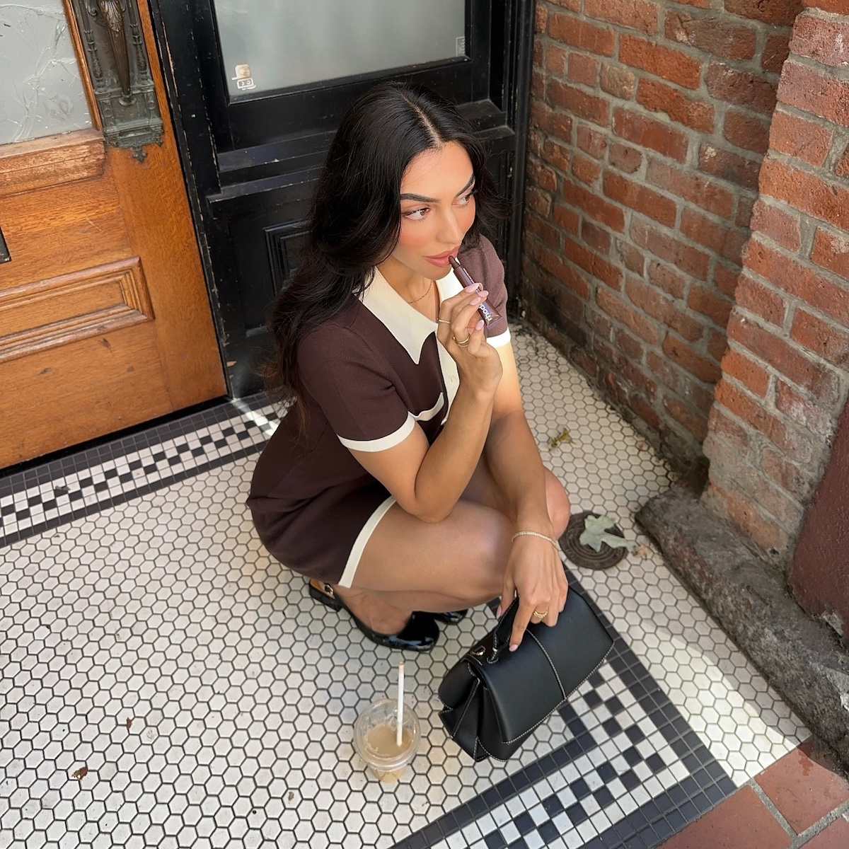 Woman applying lip gloss on a city stoop