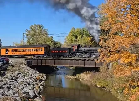 The Arcade &amp;amp; Attica steam train crossing a bridge in fall.