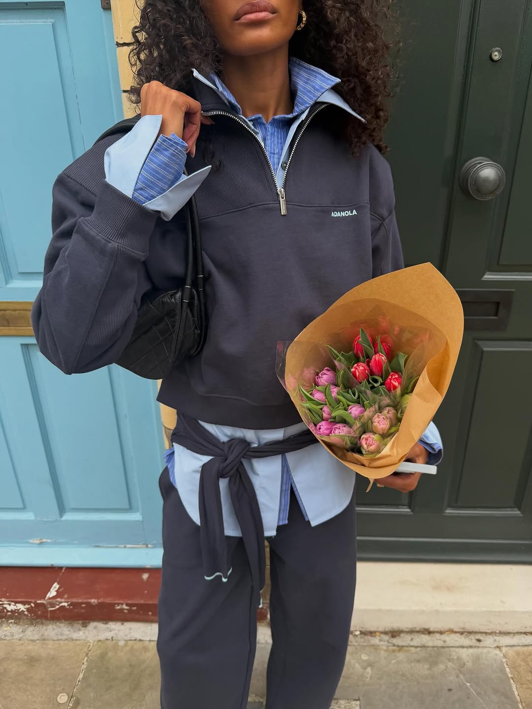A woman wearing a navy tracksuit and light blue layered button-downs, one of the biggest 2026 spring color pairings.