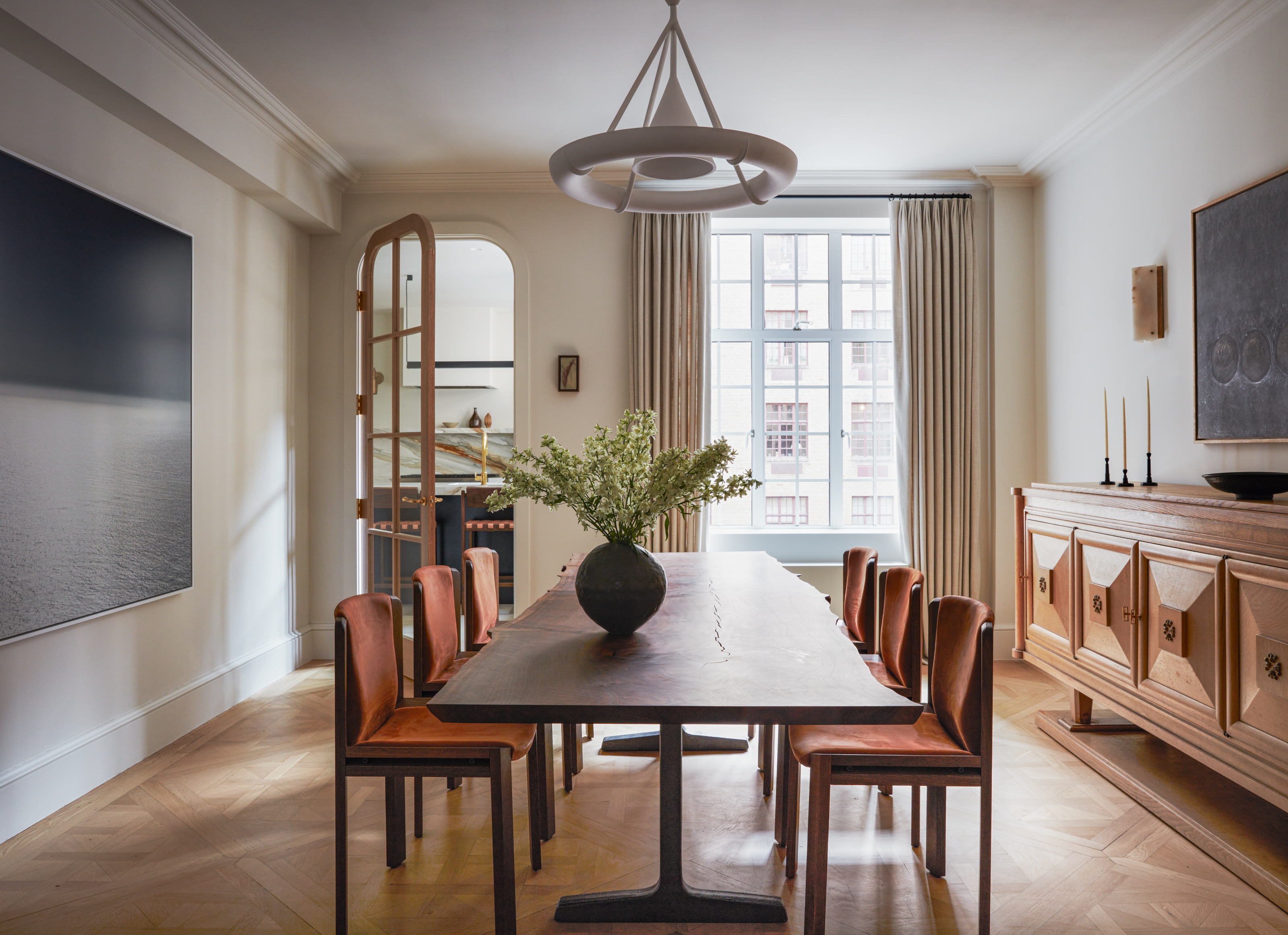Dining room with cream walls, parquet floor, dark wood rectangular dining table and rust upholstered wood chairs