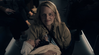 June Osborne (Elisabeth Moss) holding a newborn baby and smiling in The Handmaid's Tale season 6